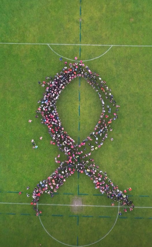 Vue aérienne des participants formant un ruban rose, par DroniDrone Adventure
